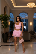 Model wearing a pink ruffle lace two-piece skort set in a luxury hotel lobby